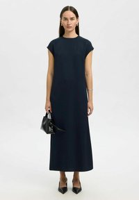 Abito maxi blu navy con maniche corte a cappuccio e silhouette dritta. Indossato con décolleté nere a punta e una piccola borsa nera. Tessuto liscio.