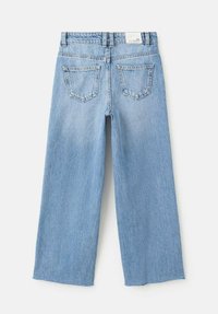Jean large en denim bleu clair avec un ourlet effiloché, comportant deux poches arrière et une étiquette standard à la taille.