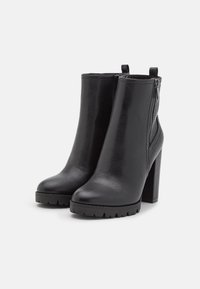 Czarne botki za kostkę wykonane z gładkiej ekologicznej skóry, z obcasem w kształcie bloku, bocznym zamkiem błyskawicznym oraz teksturowaną podeszwą dla lepszej przyczepności.
