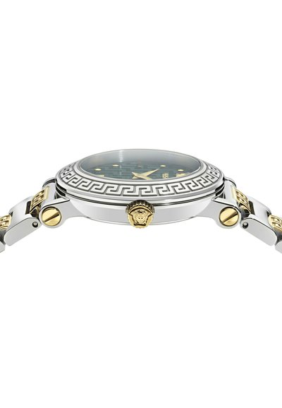 Oldalnézetű ezüst és arany karóra, mintás kerettel, arany Medúza fej koronával és arany részletekkel ellátott fém karkötővel.