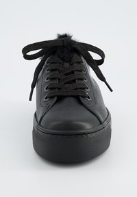 Schwarze Plateausneaker aus Leder mit strukturiertem Gummisohlenprofil, rundem Zeh, dicken schwarzen Schnürsenkeln und einem weichen schwarzen Bommel als Akzent oben.