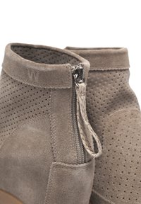 Bottines en suède gris avec des détails perforés, une fermeture éclair sur le côté avec une languette tressée, et une finition lisse au niveau des orteils.