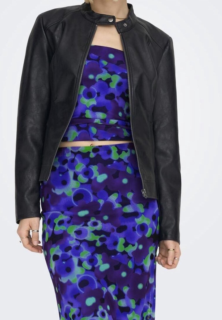 Giacca moto in pelle nera con colletto arrotondato e dettagli sui lati delle spalle, abbinata a un vestito con fantasia floreale vibrante blu e verde.