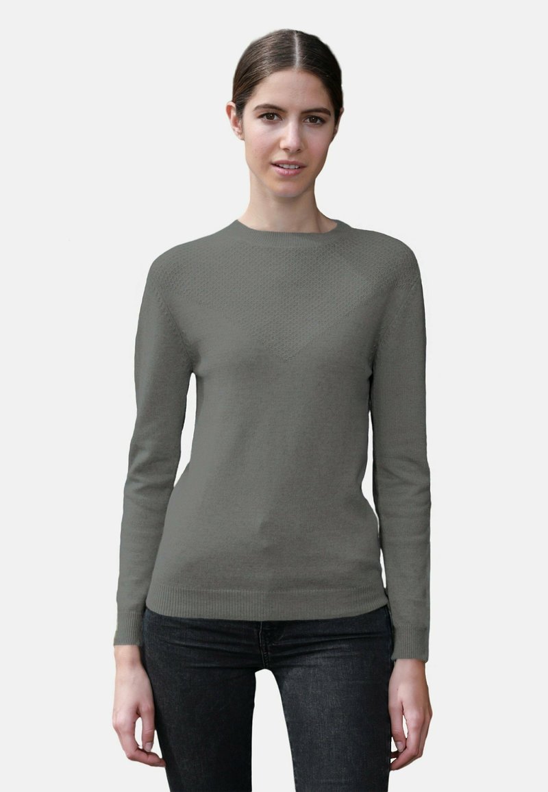 Pull-over long gris clair à manches longues avec un motif en losanges texturé, col rond et poignets et ourlet côtelés, associé à un jean noir.