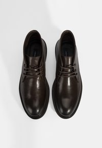 Chaussures habillées en cuir marron avec une finition lisse, bout rond et design à lacets. Elles présentent un dessus subtilement texturé et une semelle contrastante.