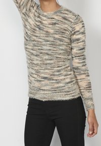 Luddig, långärmad tröja med en strukturerad randig mönstring i nyanser av beige, grått och mjuka pastelltoner. Rundad halsringning.