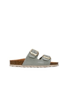Sandalia tipo slide de ante gris con punta abierta, dos hebillas ajustables en tono dorado y plantilla de corcho sobre una suela beige texturizada.