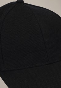 Czarna czapka bejsbolowa wykonana z fakturowanej tkaniny. Posiada zaokrągloną koronę i zakrzywiony daszek. Zawiera górny guzik i przeszycia.