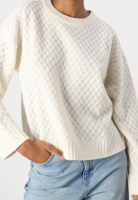 Cremefarbener Strickpullover mit strukturiertem Wabenmuster und gerippten B�ündchen. Die Passform ist lässig mit einem klassischen Rundhalsausschnitt.
