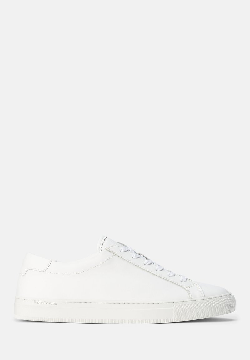 Zapatillas deportivas de cuero blancas con una textura suave, forma redondeada, suela plana de goma y cordones blancos. Presentan un diseño minimalista y una marca sutil.