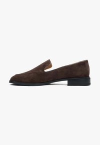 Brown suede slip-on shoe with open sides, rounded toe, and a low black rubber heel. Smooth texture with clean, minimalist design.