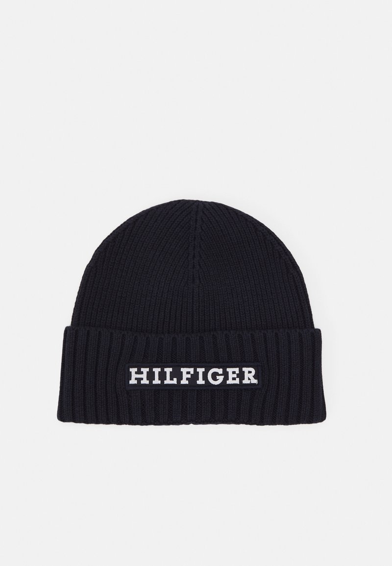 Bonnet en tricot bleu marine avec une texture côtelée et un revers replié. Présente un patch logo "HILFIGER" blanc à l'avant.