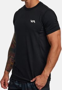 Zwart sportt-shirt van gladde, vochtafvoerende stof; heeft korte mouwen, een ronde hals en een wit logo op de borst.