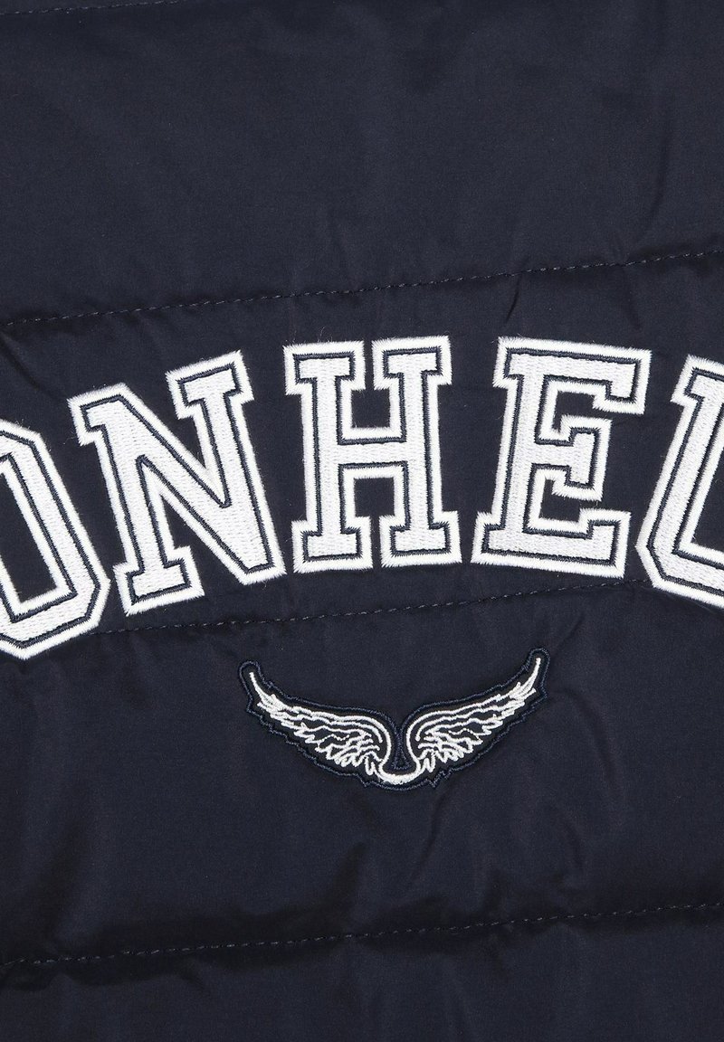 Veste matelassée bleu marine avec texte brodé "ON HEAD" en blanc et détail graphique d'ailes. Sa composition en tissu lisse et ses lignes cousues ajoutent une touche d'élégance.