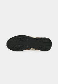 Black rubber outsole with deep treads, featuring brown, beige, and cream accents. Durable design suitable for outdoor use.