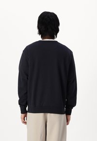 Mørkeblå sweatshirt med rund halsudskæring og lange ærmer. Lavet af blødt stof med ribbet kant og mansjetter. Ingen synlige mønstre.