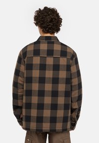 Rutigt skjorta i bruna och svarta nyanser, med krage, knäppning vid ärmslut och en texturerad tyg med en avslappnad passform.