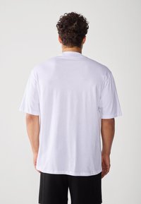 White short-sleeve t-shirt with a round neck, made of smooth fabric, featuring a relaxed fit and minimal stitching details on the back.