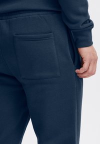 Marineblaue Jogginghosen aus weichem Stoff mit einer aufgesetzten Gesäßtasche, elastischem Bund und glatter Oberfläche.