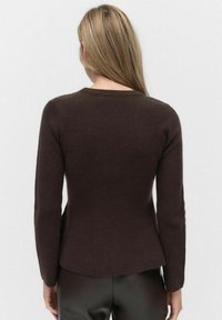 Brązowy sweter dzianinowy z długimi rękawami, dopasowanym krojem i okrągłym dekoltem. Strukturę ma prążkowaną z delikatnym naciągnięciem.