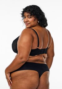 Black lace bra with adjustable straps and a hook closure, paired with black seamless underwear, showcasing smooth fabric and thong design.