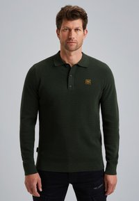 Dunkelgrünes Langarm-Polohemd aus strukturiertem Material, mit Kragen und einer dreiknöpfigen Knopfleiste. Verfügt über ein kleines gelbes Logo auf der Brust.