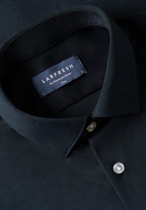 Marineblauw poloshirt van textuurstof, met een klassieke kraag, twee knopen en een label dat "LABFRESH by Kenneth Perez" zegt.