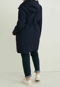 Námornícký nepromokavý kabát se staženým pasem a nastavitelnou kapucí, s elastickými manžetami a rovnými lemy. Stylizováno s tmavými džíny a teniskami.