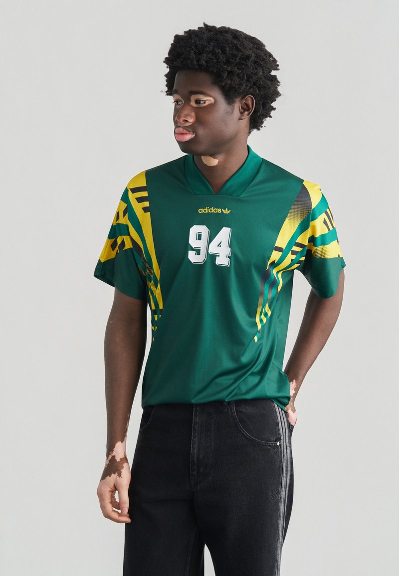 Πράσινη αθλητική φανέλα με κίτρινα και μαύρα σχέδια, με τον αριθμό 94 σε λευκό. Κατασκευασμένη από απαλό ύφασμα, με σχέ διο v-λαιμόκοψης.