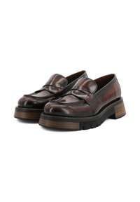 Mocasines de cuero marrón con un acabado brillante, que presentan una banda ancha en la parte frontal, suela gruesa y una suela exterior de goma negra texturizada.