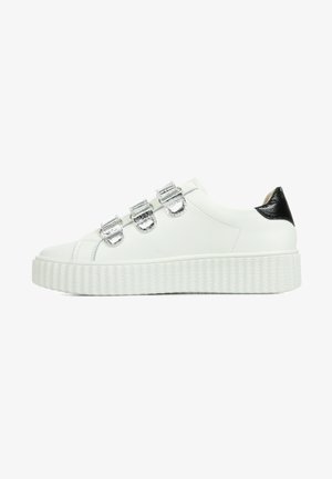 Witte leren sneaker met drie zilverkleurige metalen gespen en een zwarte accent bij de hak. Beschikt over een textuur witte platformzool.