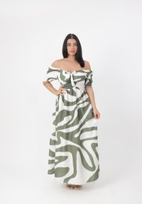 Abito maxi bianco off-shoulder con motivi astratti verdi. Presenta una parte anteriore annodata e un corpino arricciato; maniche a sbuffo corte.
