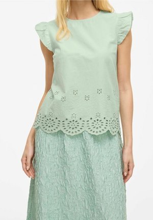 Mintgrøn top med flæser på ærmerne og laserudskåret blomsterdesign langs kanten. Matches med et tilsvarende struktureret nederdel.