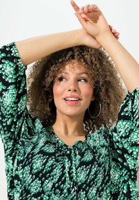 Blusa nera e verde a fantasia con maniche a sbuffo e dettaglio con fiocco frontale, caratterizzata da un tessuto testurizzato e una vestibilità comoda.