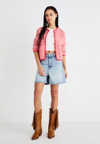 Sarkan-balts svītrots kardigans, balts īsais tops, gaiši zili džinsa īsie šorti un brūnas šerifa kurpes ar frizēm.