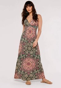 Maxikleid mit grünem, pinkem und cremefarbenem Floral-Mandala-Muster; V-Ausschnitt, tailliert und fließende Silhouette. Leichter Stoff, lässige Sandalen.