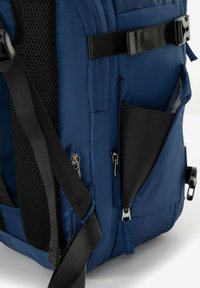 Námořnická modrá batoh s hladkým materiálem, nastavitelné černé popruhy, síťovaná část, více zipových kapes a boční kapsa s černým interiérem.