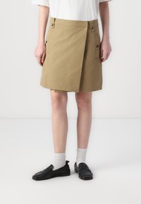 Kaki kjol i bomullstyg, med vikdesign, framknäppning, sidofickor och rak silhuett.