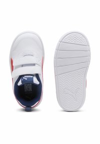 Baskets blanches avec des accents rouges, brides Velcro et une semelle texturée. L'intérieur comporte une doublure en maille bleue et le logo Puma sur la semelle intérieure.