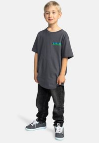 Šedé bavlněné tričko s barevným logem, černé džíny a šedé tenisky s tyrkysovými akcenty; volný střih a krátké rukávy.