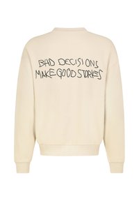 Cremfarbener Sweatshirt mit langen Ärmeln und schwarzem gesticktem Text auf dem Rücken "SCHLECHTE ENTSCHEIDUNGEN MACHEN GUTE GESCHICHTEN."