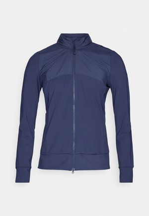 Marineblaues Zip-Jacke mit hohem Kragen, strukturierten oberen Paneelen, langen Ärmeln und gerippten Bündchen. Hergestellt aus leichtem, elastischem Stoff.