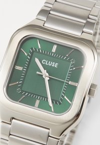 Square stainless steel watch with a green gradient dial, silver hour markers, and white hands. Features a smooth metal bracelet.