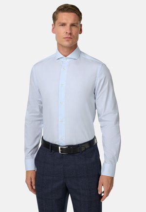 Camicia button-up azzurro chiaro con un motivo testurizzato, maniche lunghe e colletto classico, abbinata a pantaloni scuri con motivo e una cintura nera.