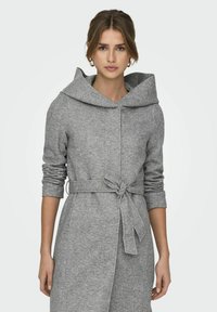 Manteau gris mi-long en tissu doux, avec une grande capuche, des manches longues, une ceinture à nouer à la taille, et des détails de couture horizontaux.