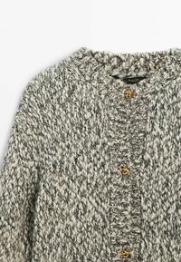 Cardigan en maille épaisse dans un fil mélangé crème et gris avec trois boutons dorés torsadés sur le devant et un col rond.