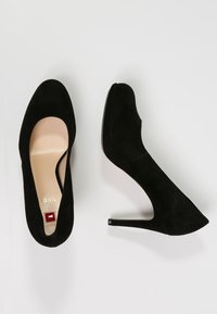 Black suede high heels with a pointed toe, featuring a small red accent near the insole. The heel is stiletto-style, offering elevation.
