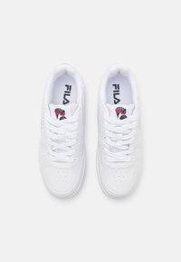 Sneaker bianche con finitura in pelle liscia, punta arrotondata, dettagli perforati e chiusura con lacci. Presenta un logo nero e rosso sulla linguetta.