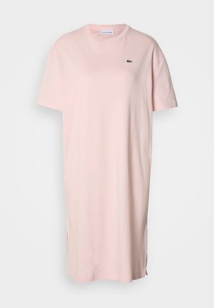 Ružové bavlnené oversized tričko šaty s krátkymi rukávmi, okrúhlym krkom a bočnými rázporkami. Na prsiach malý zelený krokodílkový logotyp.