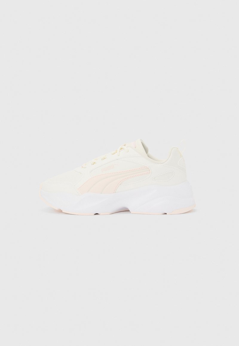 Άσπρο και ανοιχτό ροζ αθλητικό παπούτσι Puma με χοντρή σόλα, κορδόνια και λείο ανώτερο υλικό, τοποθετημένο πλαγίως σε απλό φόντο.